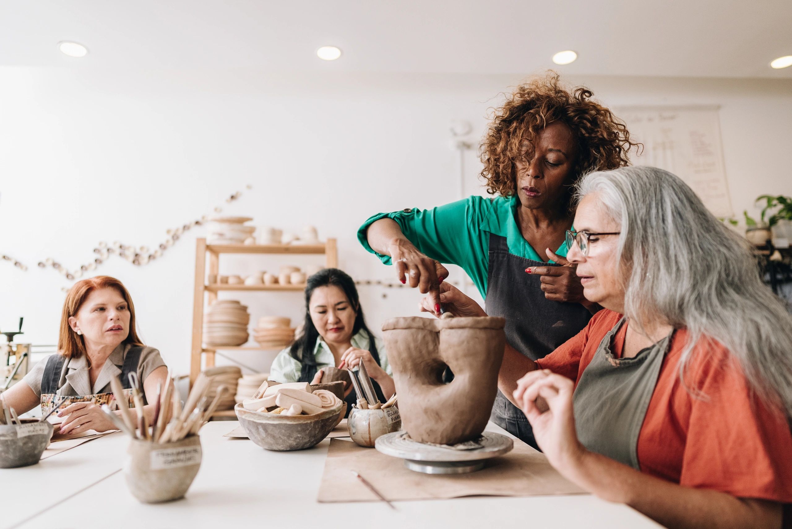 Person learning pottery skills with guidance in a ceramics workshop, representing inclusive practical training opportunities